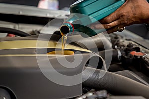 Car mechanic replacing and pouring fresh oil into engine at maintenance repair service station, Mechanic pouring oil into car at t