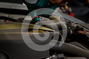 Car mechanic replacing and pouring fresh oil into engine at maintenance repair service station, Mechanic pouring oil into car at t