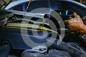 Car mechanic replacing and pouring fresh oil into engine at maintenance repair service station, Mechanic pouring oil into car at t