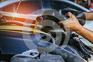 Car mechanic replacing and pouring fresh oil into engine at maintenance repair service station, Mechanic pouring oil into car at t