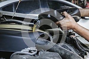 Car mechanic replacing and pouring fresh oil into engine at maintenance repair service station, Mechanic pouring oil into car at t