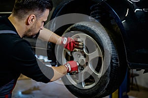 Car mechanic replacing wheel in a workshop