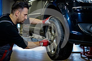 Car mechanic replacing wheel in a workshop
