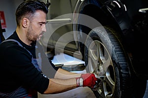 Car mechanic replacing wheel in a workshop