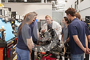 Car mechanic showing engines to apprentices