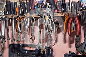 Car mechanic tools hanging on the shelf, keys, screwdrivers, pliers, scissors.