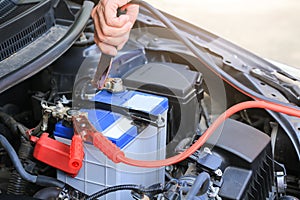 Car mechanic uses battery jumper cables charge a dead battery.