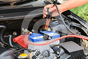 Car mechanic uses battery jumper cables charge a dead battery.