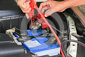 Car mechanic uses battery jumper cables charge a dead battery.