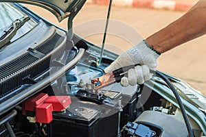 Car mechanic uses battery jumper cables to charge a dead batte