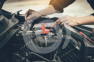 Car mechanic is using the car battery meter to measure various values and analyze it