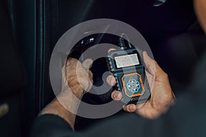 car mechanic using OBD2 scanner, code reader tool to check engine errors