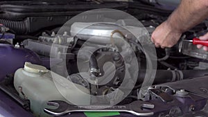 Car mechanic using a screwdriver to tighten the screws of an engine part