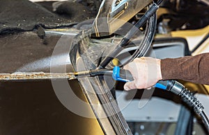 Car mechanic welds two car parts together in a service station - Serie car repair workshop photo