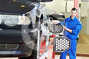 Car mechanic at wheel alignment with computer