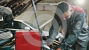 Car mechanic working in auto repair service. Auto electrician troubleshooting a car engine. Electrician working on car