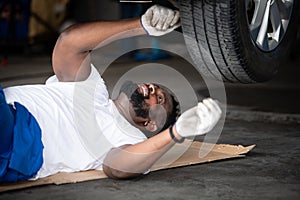 Car mechanic working in an auto repair shop, Check the operation of the engine of under the car