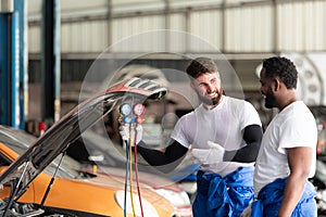 Car mechanic working in an auto repair shop, inspecting the operation of the car\'s air conditioner