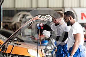 Car mechanic working in an auto repair shop, inspecting the operation of the car's air conditioner