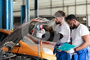 Car mechanic working in an auto repair shop, inspecting the operation of the car\'s air conditioner