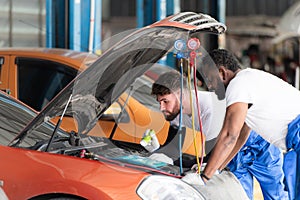 Car mechanic working in an auto repair shop, inspecting the operation of the car's air conditioner