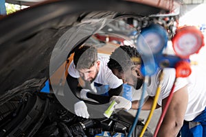 Car mechanic working in an auto repair shop, inspecting the operation of the car's air conditioner