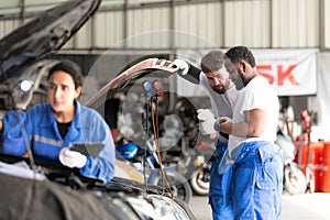 Car mechanic working in an auto repair shop, inspecting the operation of the car\'s air conditioner and refrigerant,