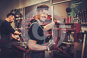 Car mechanic working with hydraulic press in auto repair service.