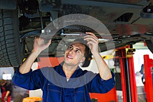 Car mechanic working on the underside of a car photo