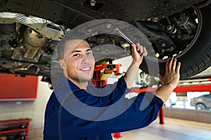 Car mechanic working on the underside of a car