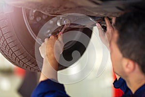 Car mechanic working on the underside of a car