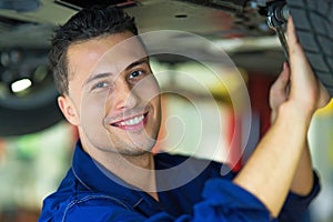 Car mechanic working on the underside of a car