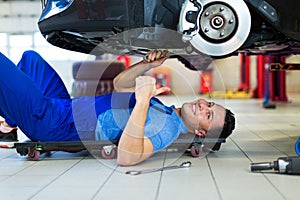 Car mechanic working on the underside of a car