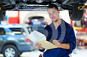Car mechanic working on the underside of a car