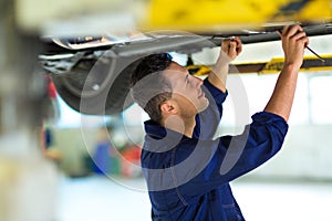 Car mechanic working on the underside of a car