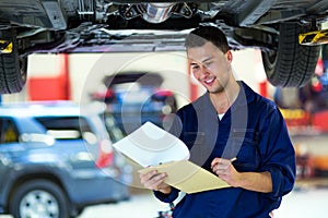 Car mechanic working on the underside of a car