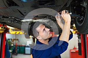 Car mechanic working on the underside of a car photo