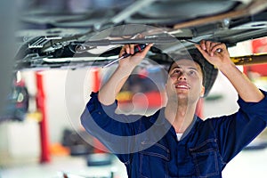 Car mechanic working on the underside of a car