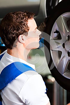 Car mechanic in workshop changing tire