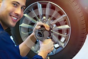 Car mechanic in workshop changing tires