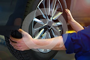 Car mechanic in workshop changing tires