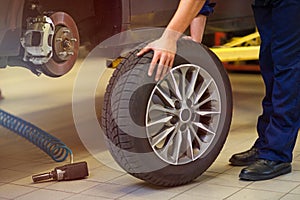 Car mechanic in workshop changing tires