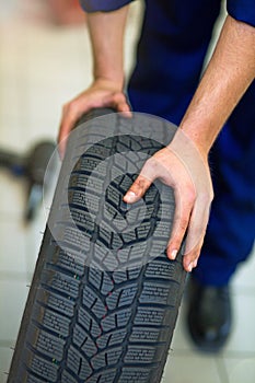 Car mechanic in workshop changing tires