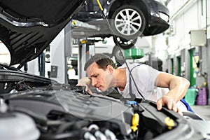 car mechanic in a workshop - engine repair and diagnosis on a vehicle