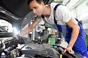 car mechanic in a workshop - engine repair and diagnosis on a vehicle