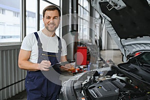 car mechanic writing while holding clipboard near cars