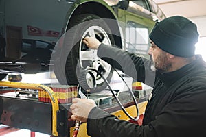 CAUCASIAN MECHANIC CHECKING THE WHEELS PRESION DURING A TUNE-UP photo