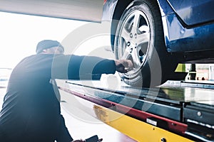 CAUCASIAN MECHANIC CHECKING THE WHEELS PRESION DURING A TUNE-UP photo