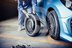 Car mechanics changing tire at auto repair shop garage. Transportation and Business working people concept. Automobile technician