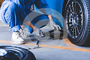 Car mechanics changing tire at auto repair shop garage. Transportation and Business working people concept. Automobile technician
